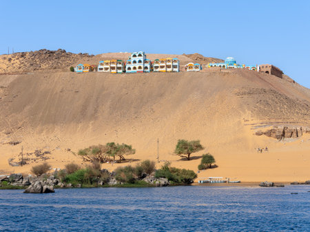 A row of colorful buildings and houses of the ancient Nubian people on the hill along the Nile in Aswan.の写真素材