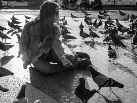 Little girl feeding pigeons in the city Barcelona.の写真素材