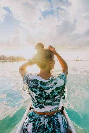 woman take a canoe ride in Bora Bora lagoon at sunsetの写真素材