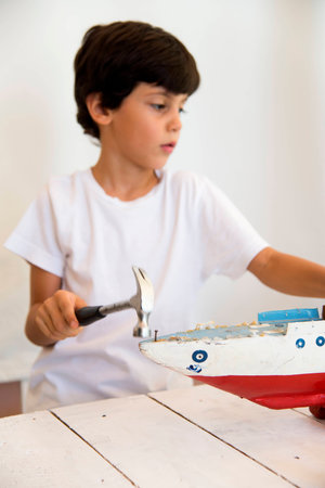 Boy painting old wooden model of a shipの写真素材