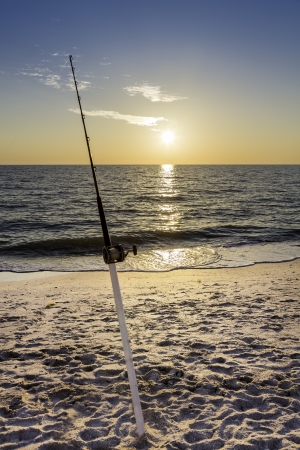 Fishing pole against ocean at sunsetの写真素材