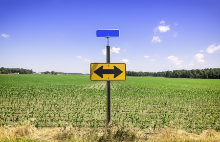 Directional arrow road sign against blue skyの写真素材