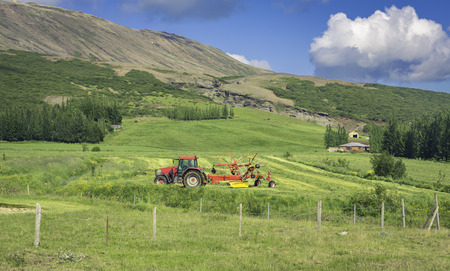 Green meadow with a tractor in high mountainsの写真素材