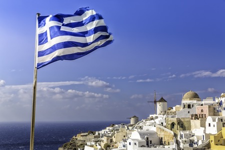 Beautiful village of Oia with Greek flag waving, Santorini Islandの写真素材