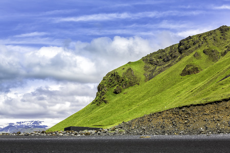 The black sand beach with typical Icelandic mountain landscapesの写真素材