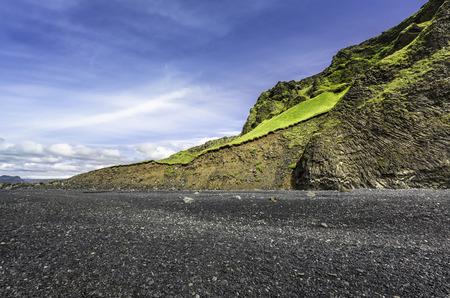 The black sand beach with typical Icelandic mountain landscapesの写真素材