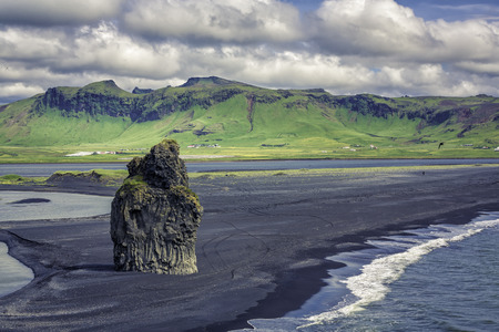 The black sand beach with typical Icelandic mountain landscapesの写真素材