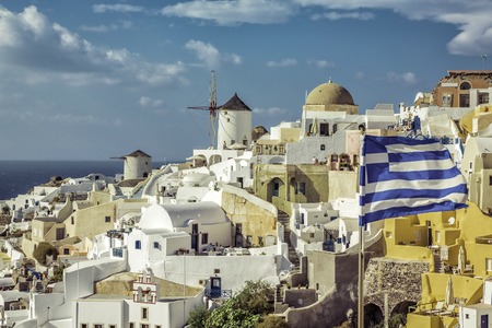 Village of Oia against greek waving flag on Santorini Island, Greeceのeditorial素材