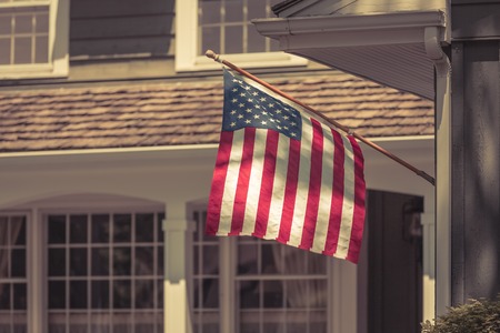 American flag wawing in front of typical american house. Vintage colorsの写真素材