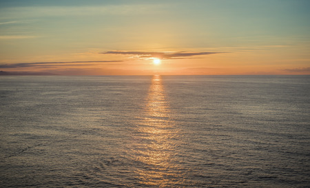 Sunset aboove the ocean horizont, reflection on water surfaceの写真素材