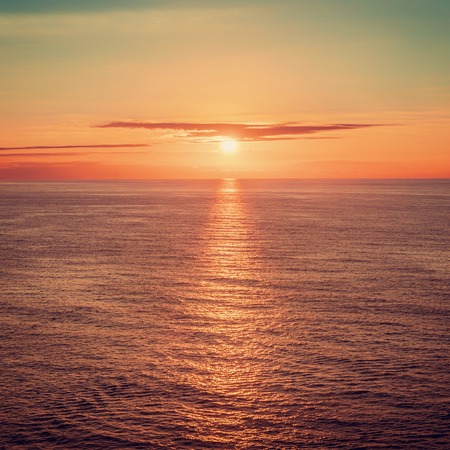 Sunset aboove the ocean horizont, reflection on water surfaceの写真素材