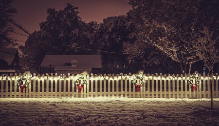 Seasonal Illuminated Christmas Decoration on white fence. Vintage colorsの写真素材