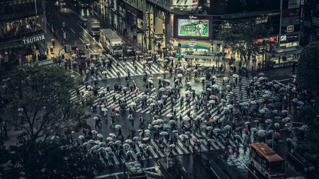 Shibuya scramble crossing, one of the busiest pedestrian crossing in the world, Japan. People crossing the street on rainy evening with umbrellas.のeditorial素材