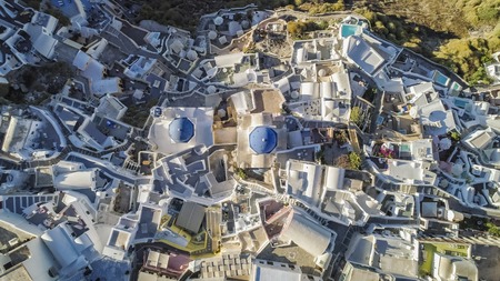 Aerial top view of white houses and blue dome church in Oia village, Santorini Island, Greeceの写真素材