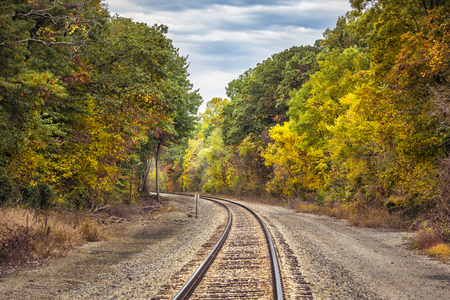 Railway track with a curve surrounded by trees in autumn colorsの写真素材
