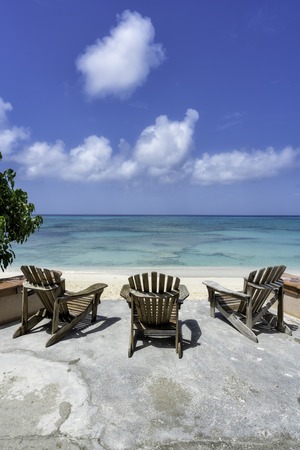 Wooden beach chairs in front of tropical oceanの写真素材