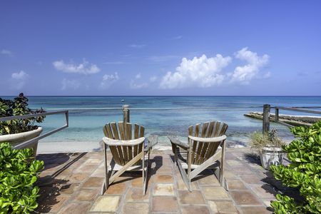 Wooden beach chairs in front of tropical oceanの写真素材