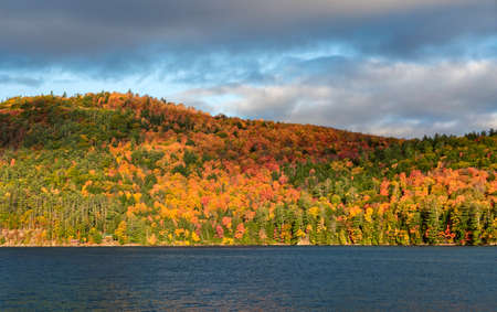 Foliage in Vermont. Multicolor trees on the hills by the lakeの写真素材