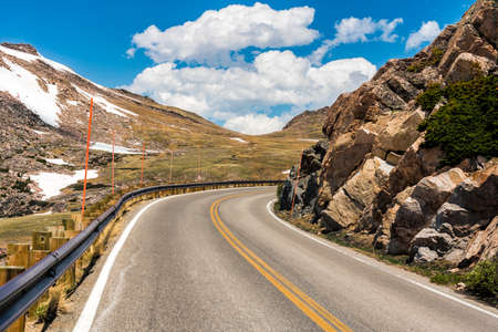 Asphalt winding road surrounded by rocks with snow in high Wyoming mountainの写真素材