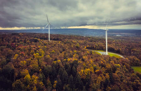 Wind turbines on the top of Vermont mountains, aerial view, fall season with cloudy sky