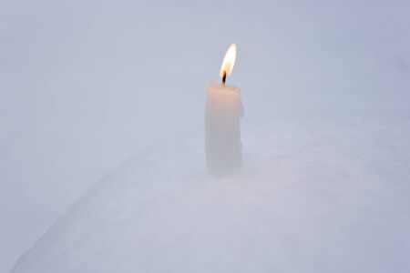 Burning candle on real snow. Christmas festive backgroundの写真素材