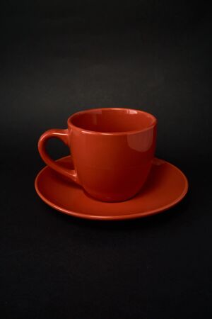 Red cup of coffee and saucer on a black backgroundの写真素材