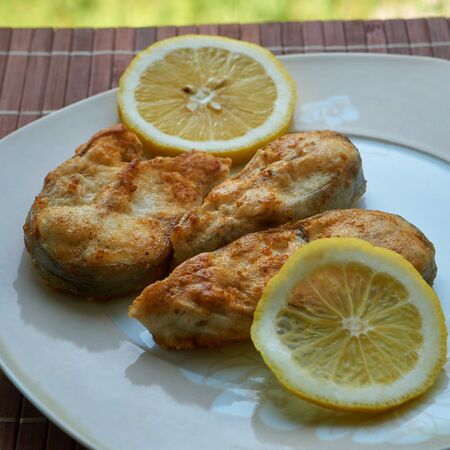 Pieces of fried fish with lemon wedges.の写真素材