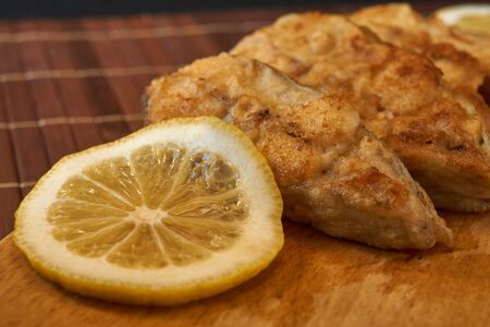 Pieces of fried fish with lemon wedges.の写真素材