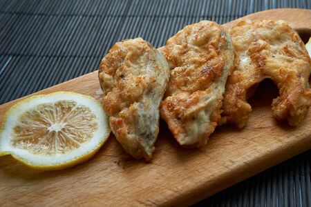 Pieces of fried fish with lemon wedges.の写真素材