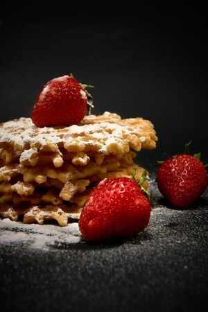 Crispy sweet waffles with fresh strawberries, on a dark backgroundの写真素材
