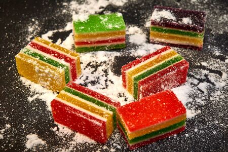 Slices of marmalade in icing sugar on a black backgroundの写真素材