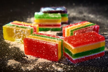 Slices of marmalade in icing sugar on a black backgroundの写真素材