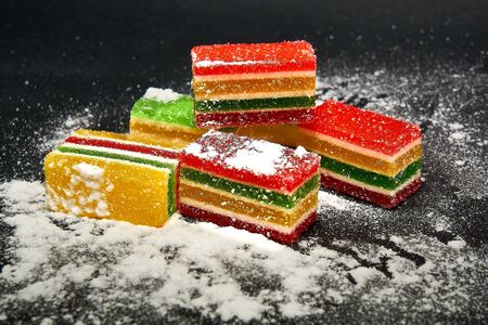 Slices of marmalade in icing sugar on a black backgroundの写真素材