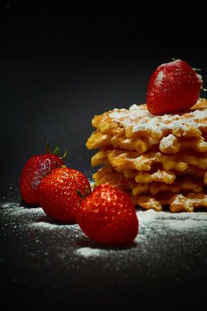 Crispy sweet waffles with fresh strawberries, on a dark backgroundの写真素材