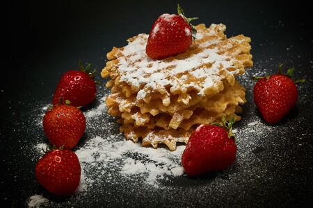 Crispy sweet waffles with fresh strawberries, on a dark backgroundの写真素材