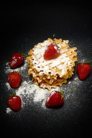 Crispy sweet waffles with fresh strawberries, on a dark backgroundの写真素材