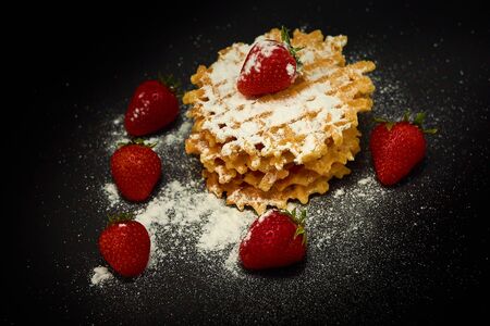 Crispy sweet waffles with fresh strawberries, on a dark backgroundの写真素材