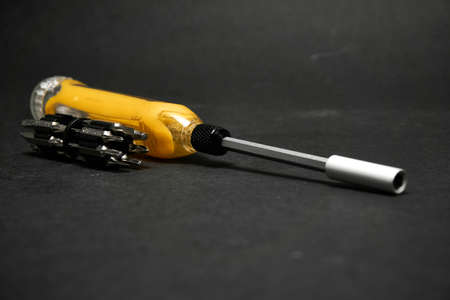 Screwdriver with a universal set of bits, on a dark backgroundの写真素材