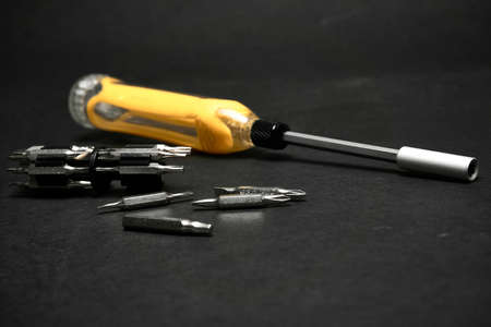 Screwdriver with a universal set of bits, on a dark background