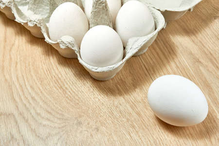 Raw chicken eggs in a cardboard box on the table.