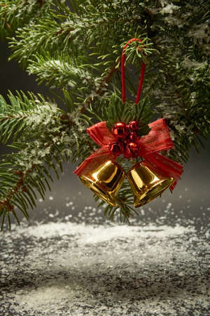 Christmas decoration with bells, a branch of a Christmas tree and artificial snow on a black backgroundの写真素材