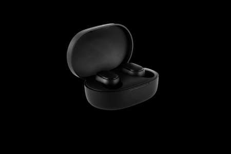 Wireless headphones on a black background. Close-up. Bluetooth headset in charging case