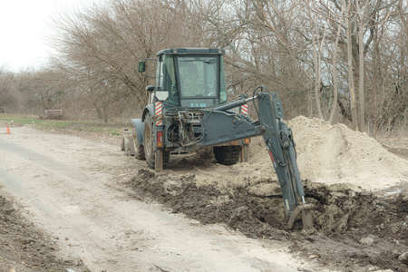 Backhoe loader digging hole, road works