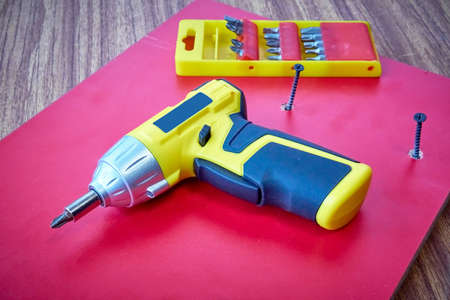 Cordless screwdriver with a set of nozzles on a red board, DIY repairの写真素材