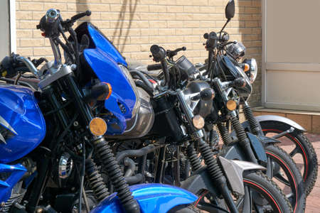 Row of motorcycles parked near the building on the streetの写真素材
