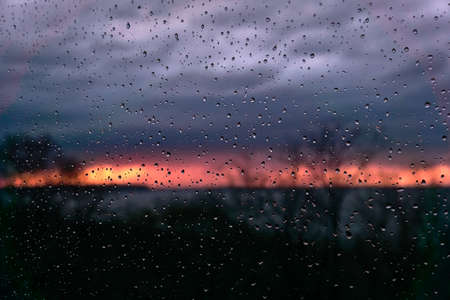 Raindrops on the glass, against the background of a crimson sunset, a slight blurの写真素材