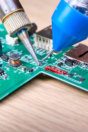 Repair of electronic boards with a soldering iron and tin wire, computer equipment, mobile phone, electronics, repair, upgrade and technology repair concept.の写真素材