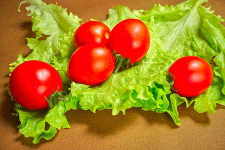 Red cherry tomatoes lie on a lettuce leafの写真素材