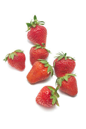 Home-grown strawberries are bright red in color with green leaves on a white background. Strawberries are fresh, with visible seeds on the surfaceの写真素材