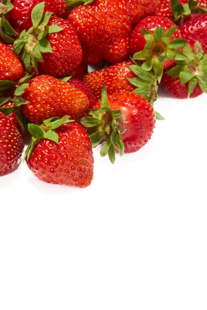 Group of ripe strawberries in bright red color with green leaves, gathered together in a pile on a white backgroundの写真素材